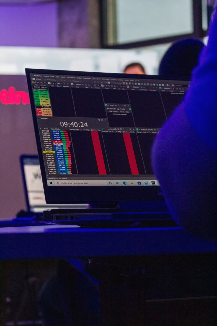 Close-up of a person analyzing data on a laptop at a desk with a digital interface displayed.