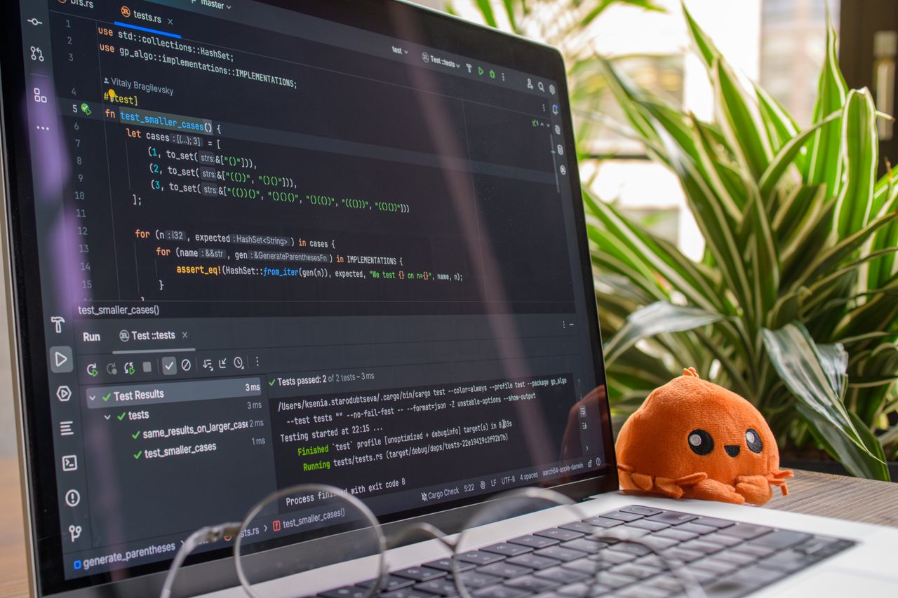 A laptop displaying code in a modern indoor setting with an orange plush toy nearby.
